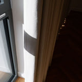 Window with a curtain partially drawn, showing a dark room beyond