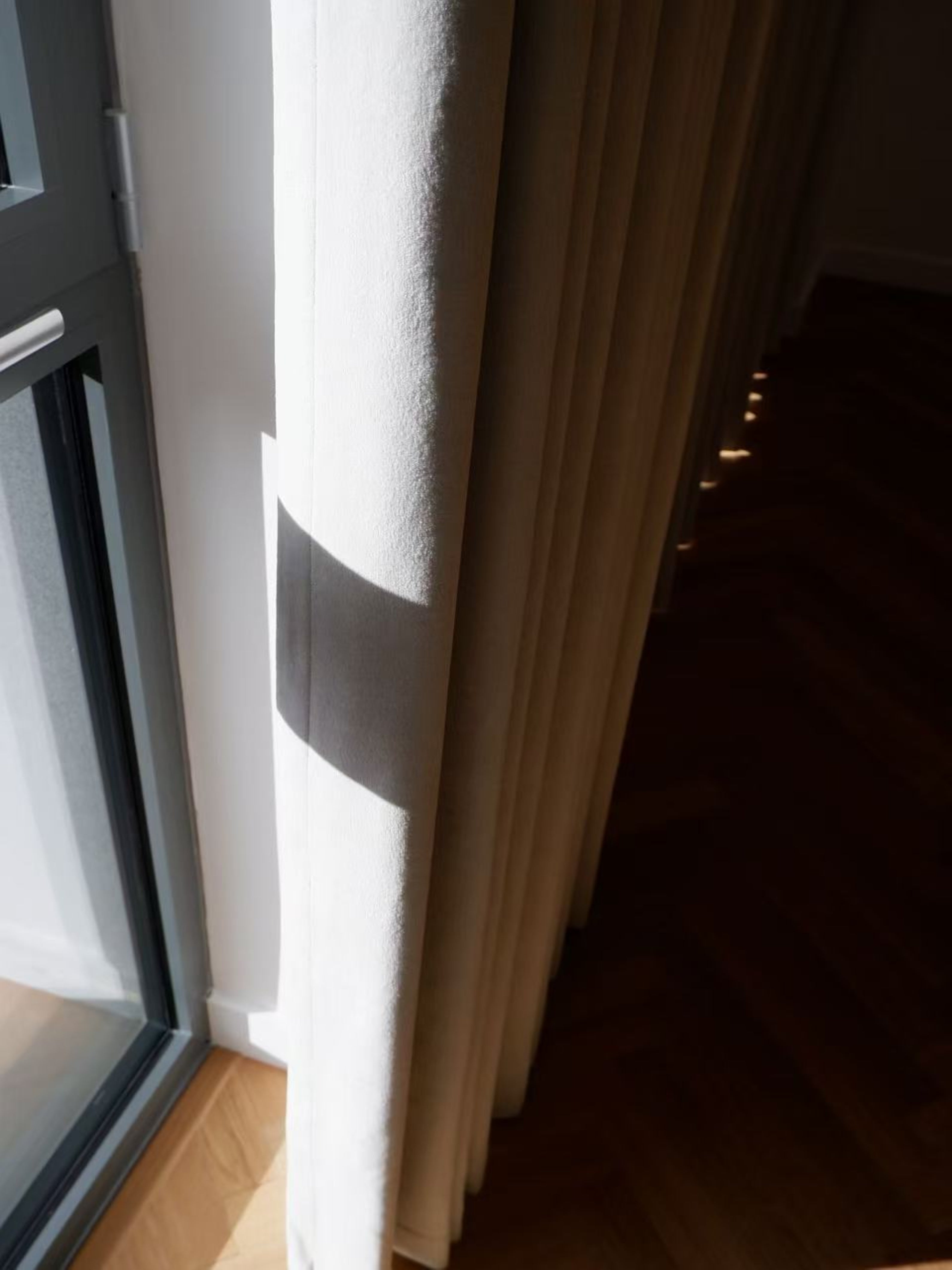 Window with a curtain partially drawn, showing a dark room beyond